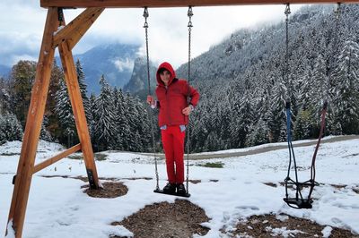 Red standing on snow covered land against mountains