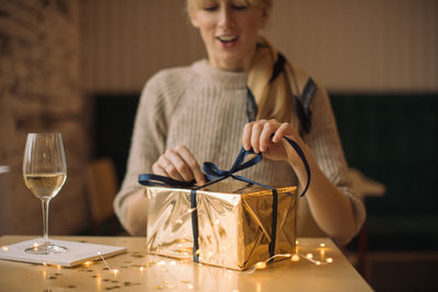 Midsection of woman holding wine glass on table