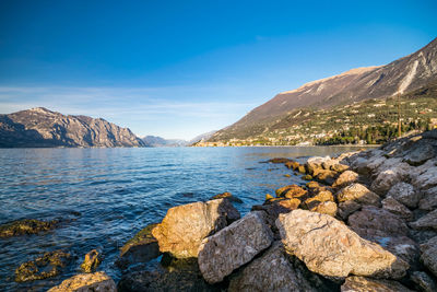 Scenic view of sea and mountains against blue sky