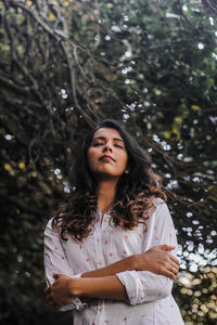 Portrait of beautiful young woman standing in forest