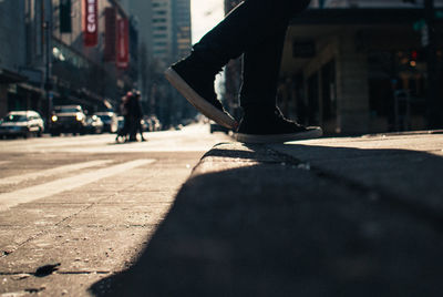 Low section of person walking on sidewalk in city
