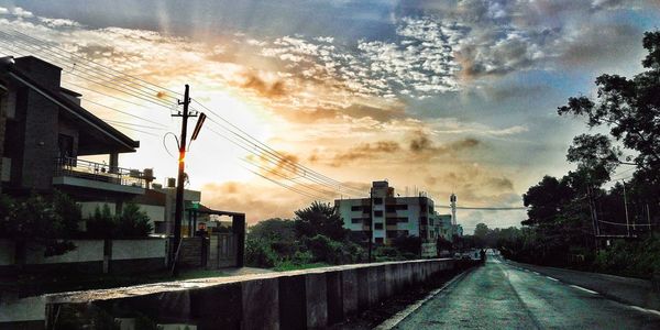 Street amidst buildings against sky during sunset