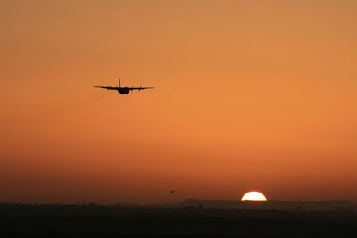 Low angle view of silhouette airplane against sky during sunset