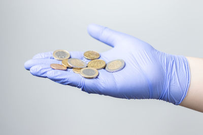 Close-up of hand holding coins over white background