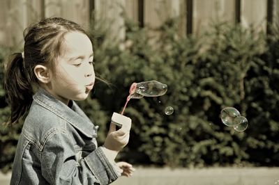 Side view of girl holding bubbles