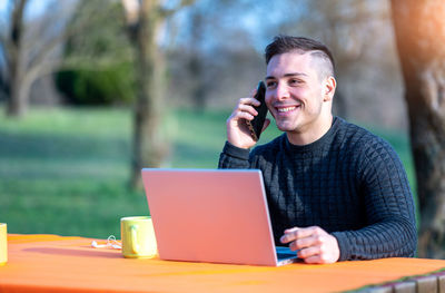 Young man using laptop while sitting on table