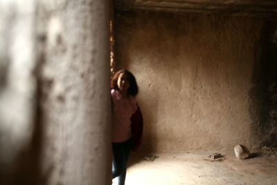 Portrait of woman standing against wall in building