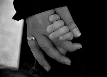 Close-up of couple holding hands against black background