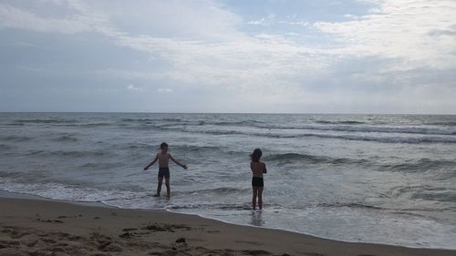 Silhouette people standing on beach against sky