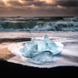 View of ice berg on beach during sunset