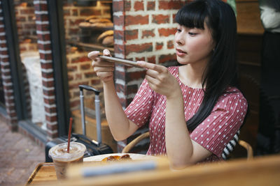 Young woman looking at sweet food in cafe