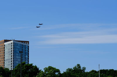 Low angle view of airplanes flying in sky over city