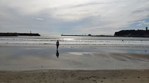 Man walking on beach against sky