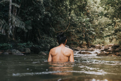 Rear view of shirtless man in water