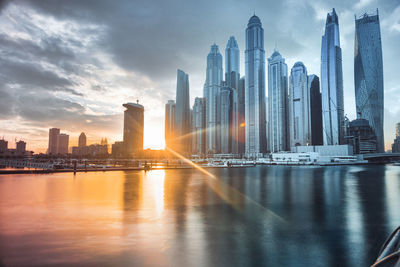 Modern buildings in city against sky during sunset