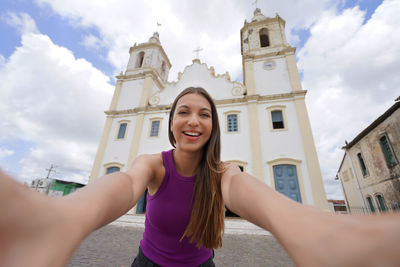 Low angle view of young woman standing against sky