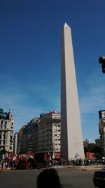 People in front of historical building against blue sky