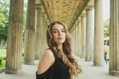 Portrait of young woman standing against building