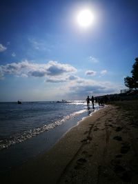 People walking on beach against sky
