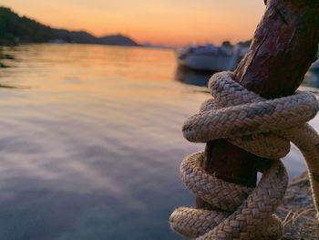 Close-up of rope on rock at beach against sky during sunset