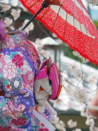 Midsection of woman wearing kimono with red umbrella against cherry tree