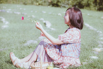 Side view of young woman with arms raised in park
