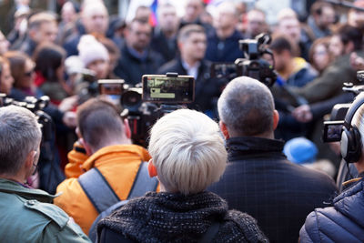 Rear view of people photographing on street in city