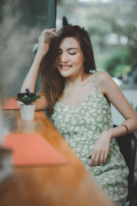 Beautiful young woman sitting with arms raised