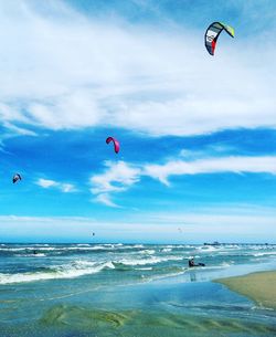 Paragliding over beach against sky