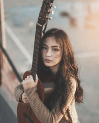 Portrait of young woman holding guitar