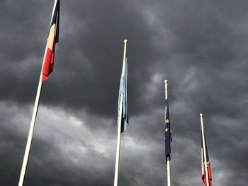 Low angle view of flags against cloudy sky