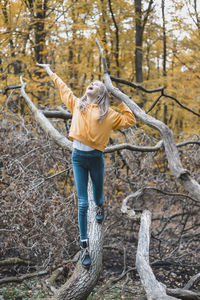 Full length of girl standing on tree trunk in forest