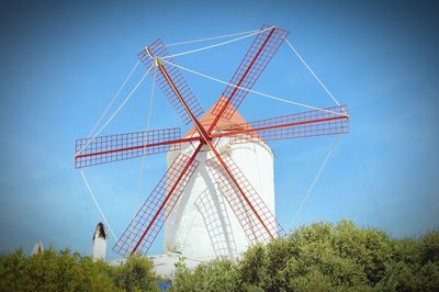 Low angle view of traditional windmill against blue sky