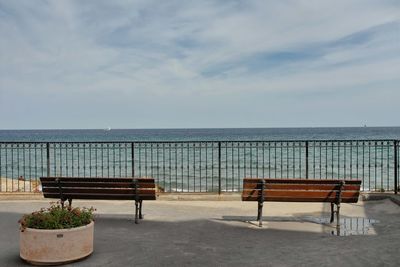 Lounge chairs by sea against sky