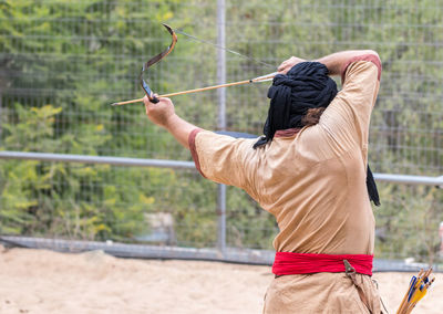 Rear view of man targeting with archery bow