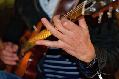 Midsection of man playing guitar