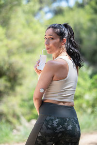 Side view of young woman holding plant