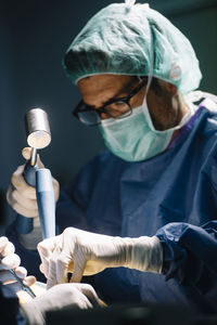 Male surgeon using hammer while doing ankle surgery in operating room