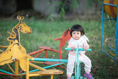 Portrait of cute girl sitting on equipment in playground