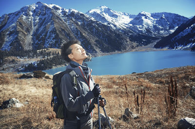 Woman with eyes closed standing at mountain lake