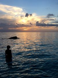 Silhouette of man in sea at sunset