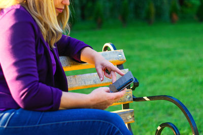 Midsection of woman using mobile phone while sitting on grass