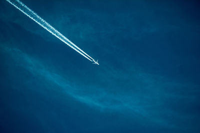 Low angle view of airplane flying against blue sky