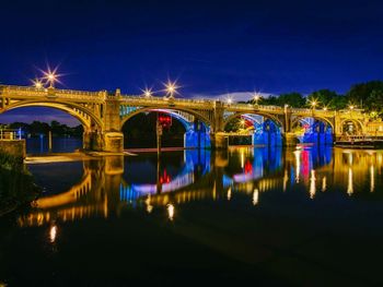 Illuminated bridge over river at night