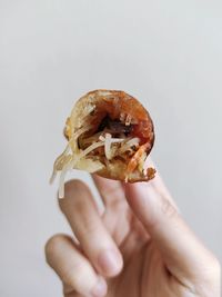 Close-up of person holding ice cream cone against white background