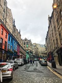 People on city street amidst buildings against sky