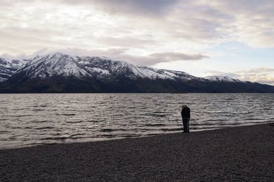 Man standing on snowcapped mountain against sky