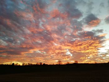 Silhouette landscape against dramatic sky during sunset