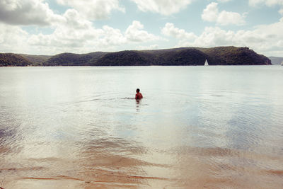 Man swimming in sea against sky