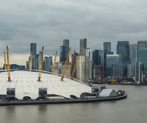 Modern buildings by river against sky in city